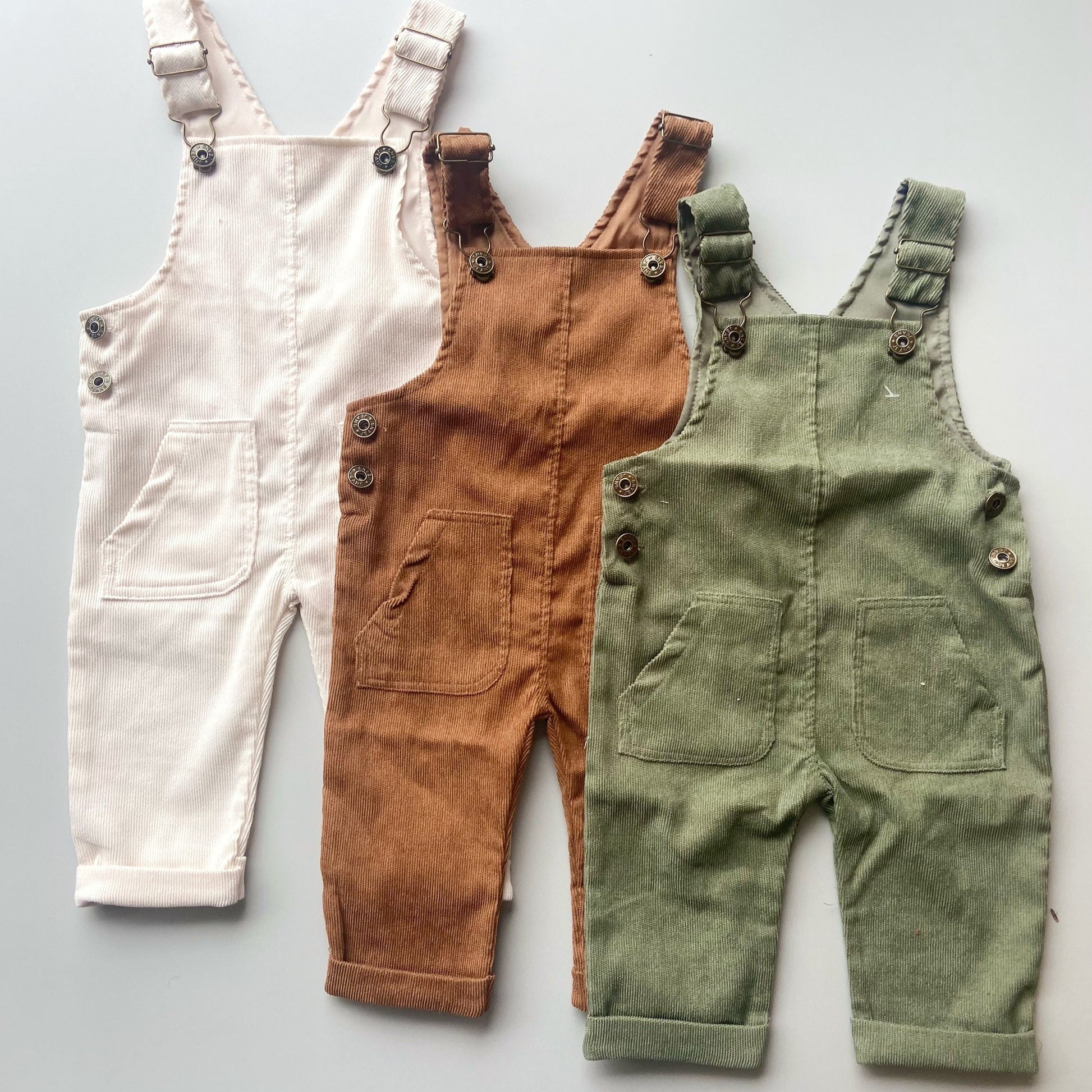 Overall para bebé en pana ligera, disponible en verde oliva, café y blanco